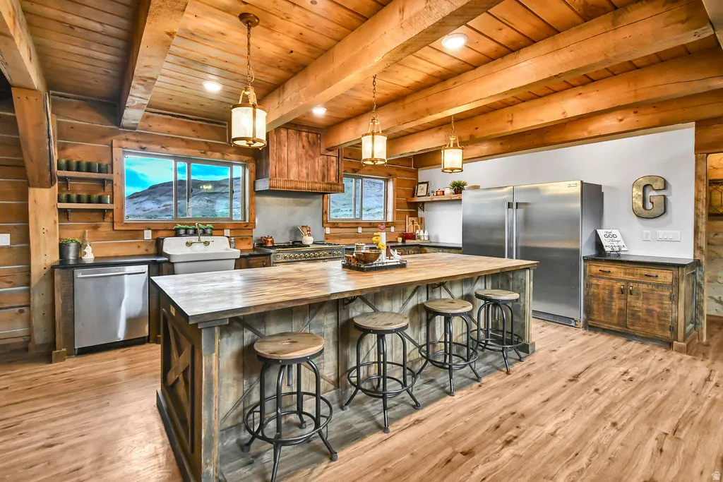 Rustic-inspired kitchen featuring a large wood-finish island, exposed wood ceiling beams, and wood-finish flooring