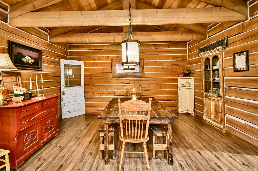 Interior space featuring wood-finish flooring, exposed wood beam ceiling, wood plank walls, and a prominent central chandelier