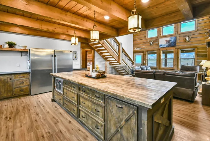 Expansive kitchen island featuring a wood-finish countertop, integrated beverage refrigerator, and distressed cabinetry