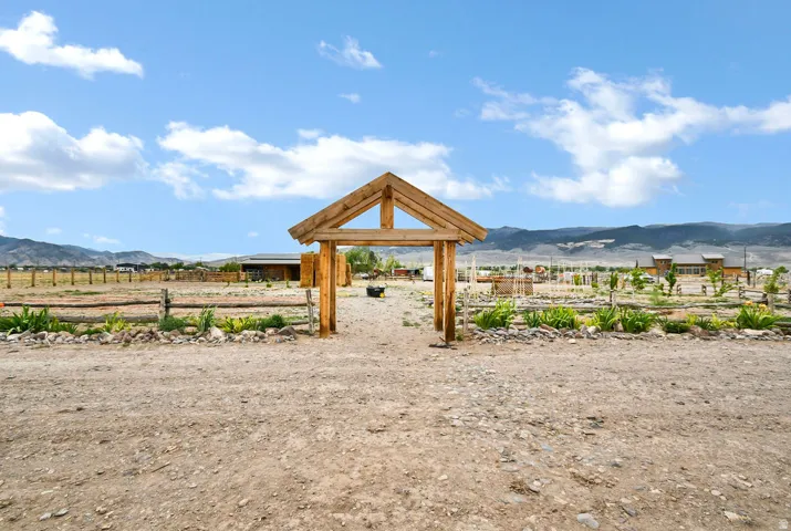 Outdoor property featuring a rustic timber frame gateway, split rail fencing, and cultivated garden beds
