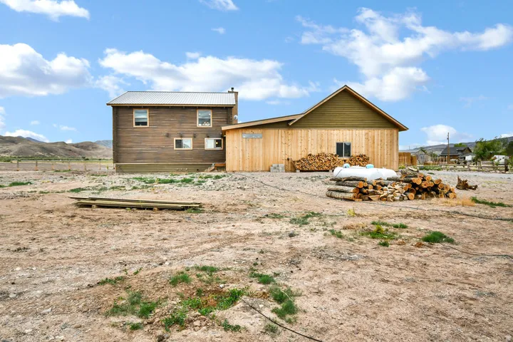 Rear exterior featuring wood siding and a metal roof