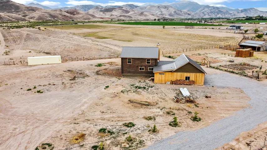 Rural property featuring a two-story residence with a metal roof and a detached outbuilding with natural wood siding