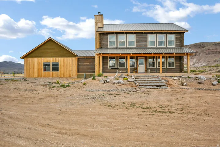 Two-story residence featuring a metal roof, wood siding, and an expansive covered front porch with supporting columns