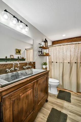 Distressed wood vanity featuring a trough sink, wall-mounted faucets, and a paneled wood backsplash