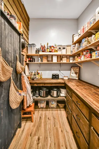 Expansive pantry featuring wood-finish flooring, custom wood cabinetry, extensive open shelving, and butcher block countertops