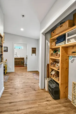 Hallway featuring wood-finish flooring, white baseboards, and light gray walls