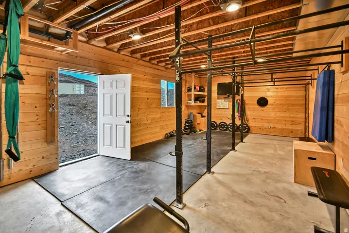 Finished basement space featuring exposed wood ceiling joists and wood-paneled walls