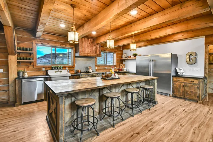 Rustic-inspired kitchen featuring a large wood-finish island, exposed wood ceiling beams, and wood-finish flooring