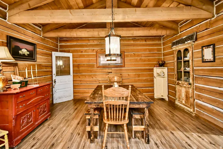 Interior space featuring wood-finish flooring, exposed wood beam ceiling, wood plank walls, and a prominent central chandelier