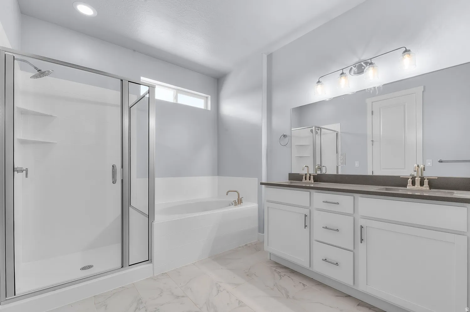 Bathroom featuring a glass-enclosed shower, a built-in soaking tub, and a double vanity with an expansive mirror