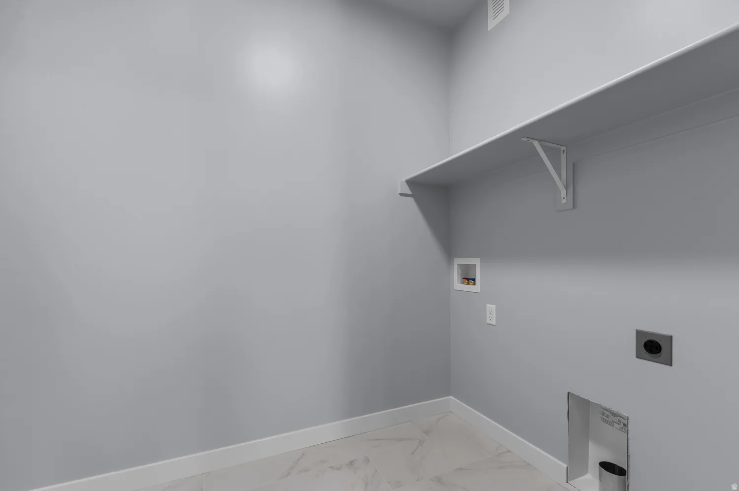 Utility room featuring a built-in shelf, light gray wall paint, and white baseboards