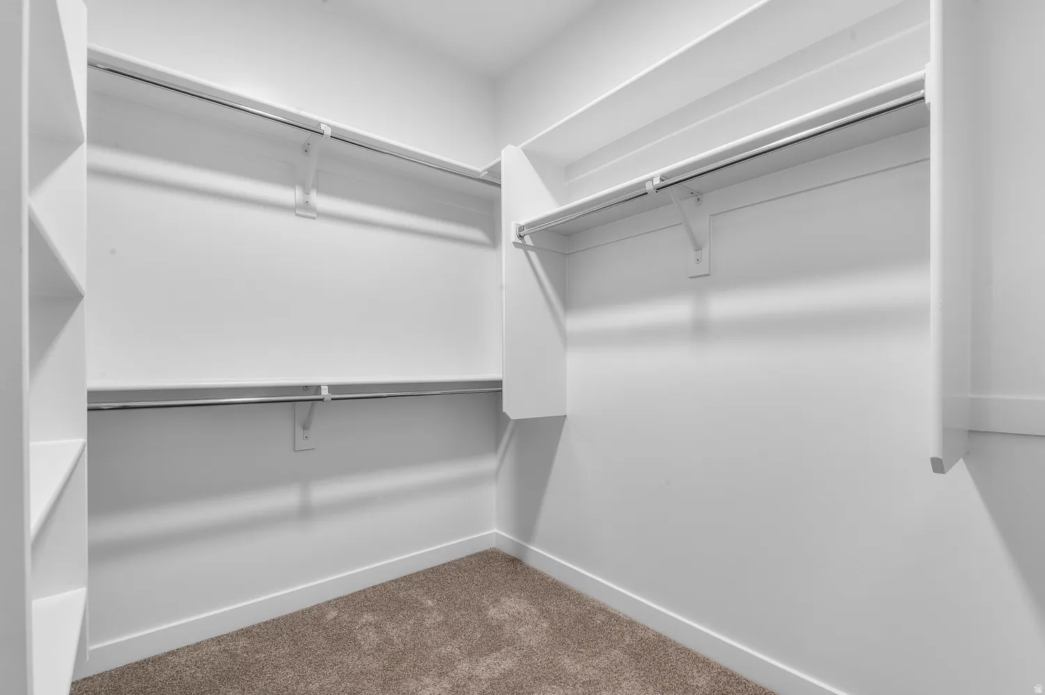 Walk-in closet featuring built-in shelving, white walls, white baseboards, and carpet flooring
