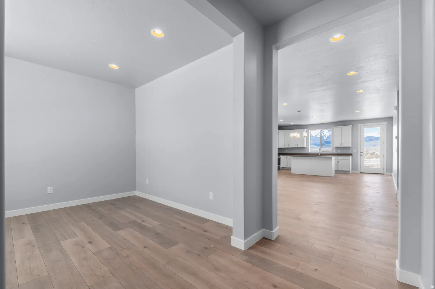 Open-concept living space featuring wood-finish flooring, recessed lighting, and a neutral color palette