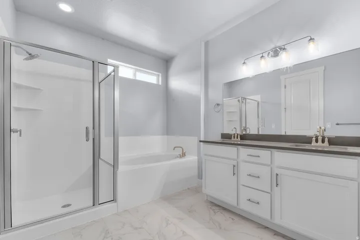 Bathroom featuring a glass-enclosed shower, a built-in soaking tub, and a double vanity with an expansive mirror