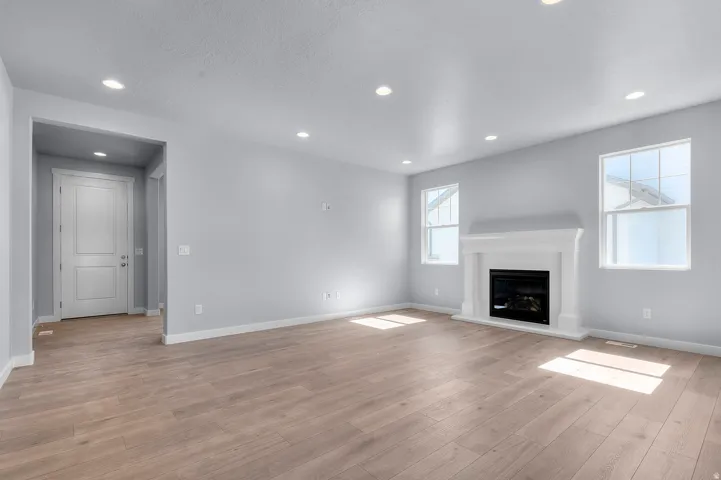 Spacious interior room featuring wood-finish flooring, recessed lighting, and a white mantel fireplace