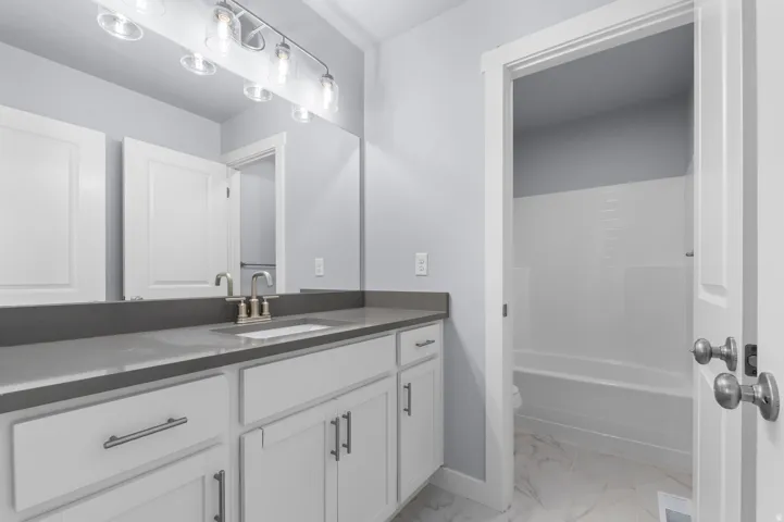 Bathroom vanity featuring a quartz-finish countertop and white shaker-style cabinetry