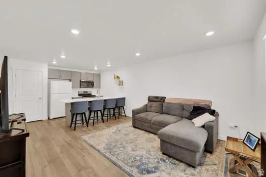 Open-concept living space featuring wood-finish flooring, recessed lighting, and a white color palette