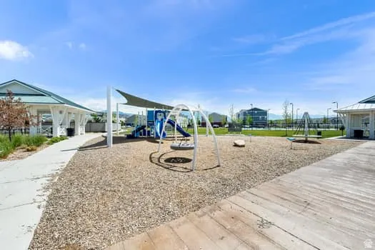 Community playground featuring modern play structures, a blue slide, and swing sets over a wood chip surface