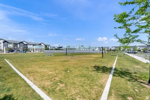 Expansive community green space featuring a recreation net, painted court lines, and a playground structure in the background