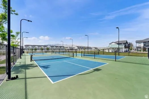 Multiple outdoor courts featuring blue playing surfaces, green surrounds, and perimeter fencing