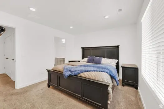Bright bedroom featuring neutral-toned carpeting and white walls