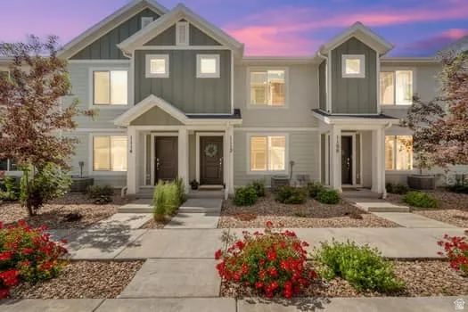 Modern townhouse exterior featuring a multi-toned facade, gabled entryways, and mature landscaping