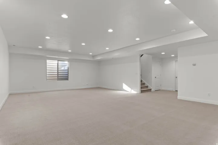 Expansive room with neutral carpet flooring and recessed lighting