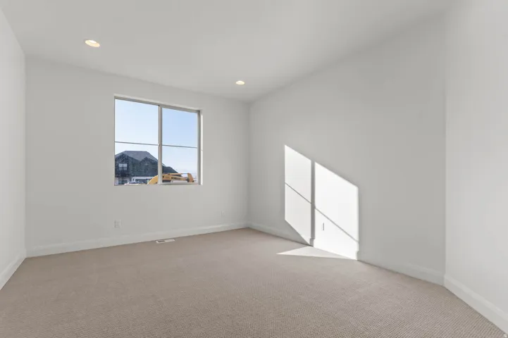 Room featuring recessed lighting, a single window with grid panes, neutral-toned carpeting, white baseboards, and white painted walls