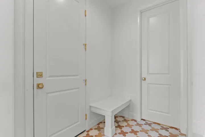 Entry area featuring white walls, white doors with gold hardware, and a built-in white bench