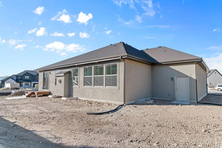 Contemporary stucco exterior featuring a dark asphalt shingle roof, multiple large windows, and a sliding glass door