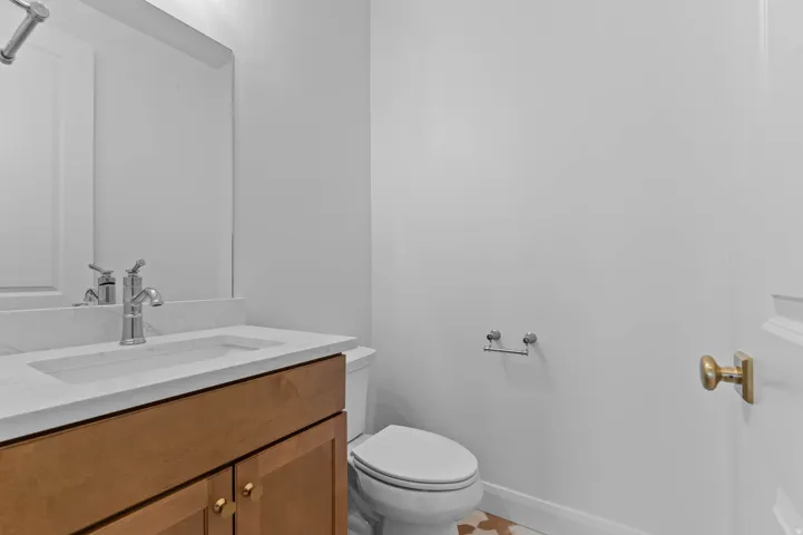 Bathroom featuring a wood-finish vanity with gold-tone hardware, a white countertop with an integrated sink, and a chrome faucet