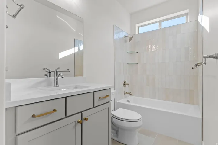 Modern bathroom featuring a single vanity with a white countertop and gray cabinetry with brass hardware