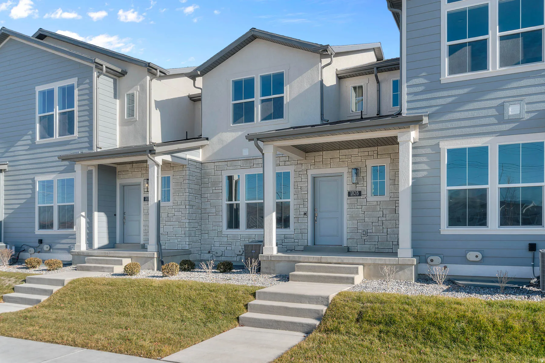 Contemporary townhome exterior featuring light blue siding and stone veneer accents