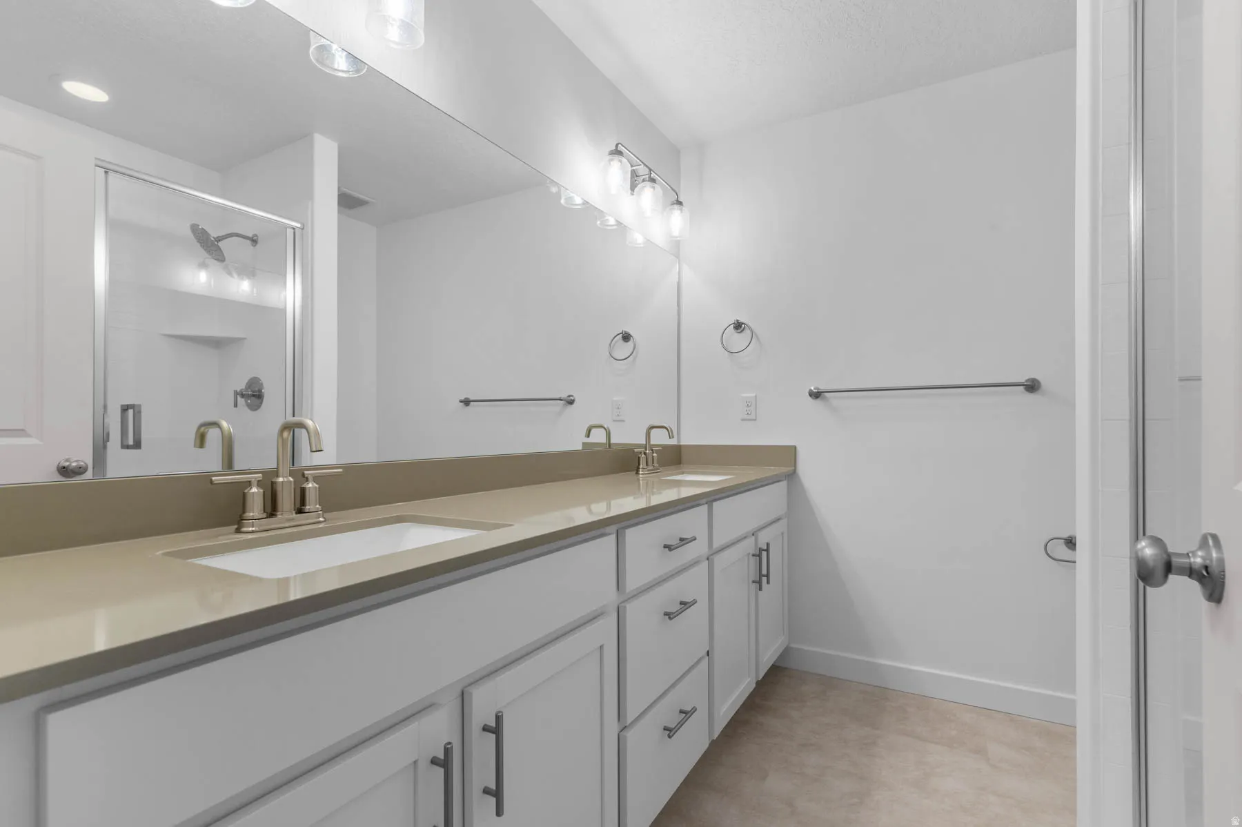 Bathroom featuring a double vanity with light-toned countertops and white cabinetry