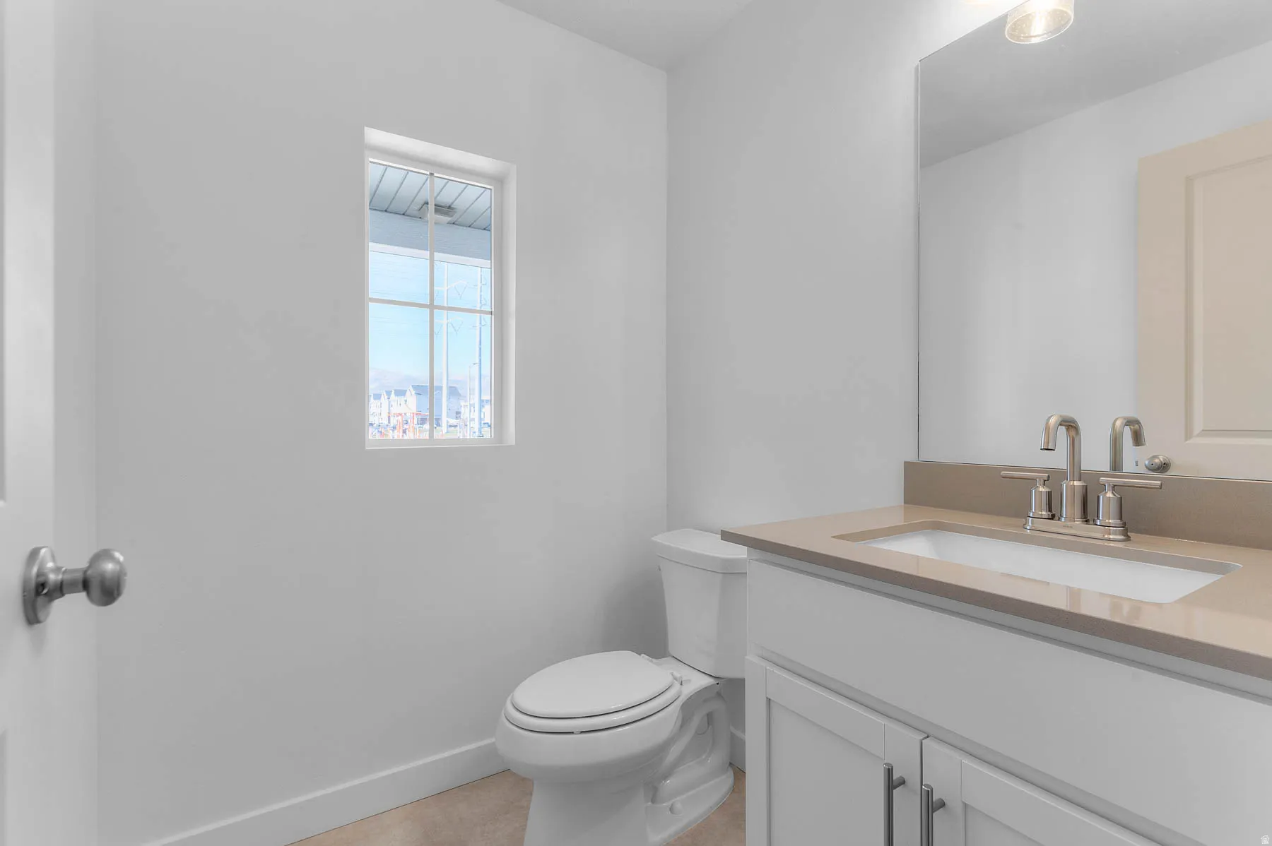 Bathroom featuring a single vanity with a light-colored countertop, undermount sink, and brushed nickel faucet
