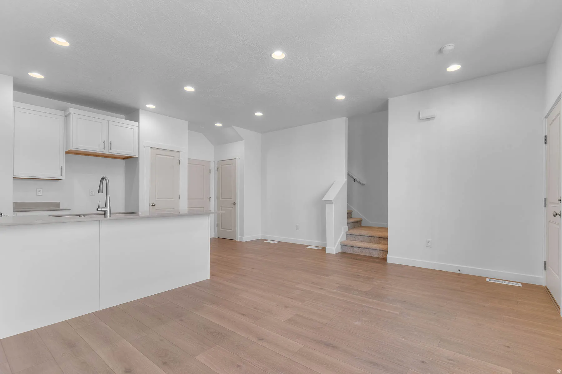 Open-concept living space featuring wood-finish flooring, recessed lighting, and a neutral color palette