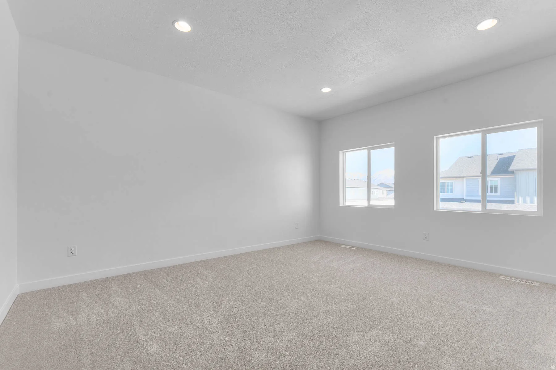 Spacious room featuring neutral carpeting and white walls