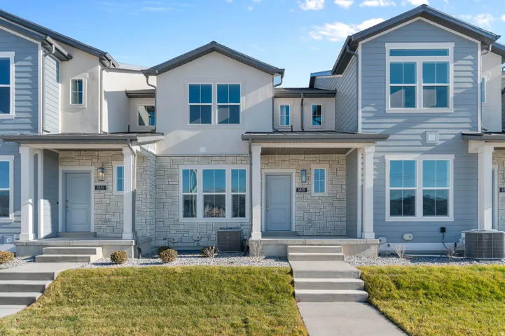 Contemporary townhome facade featuring a covered front porch and stone veneer detailing