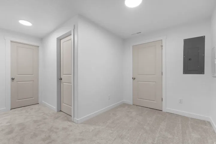 Interior hallway featuring light beige carpeting and white walls