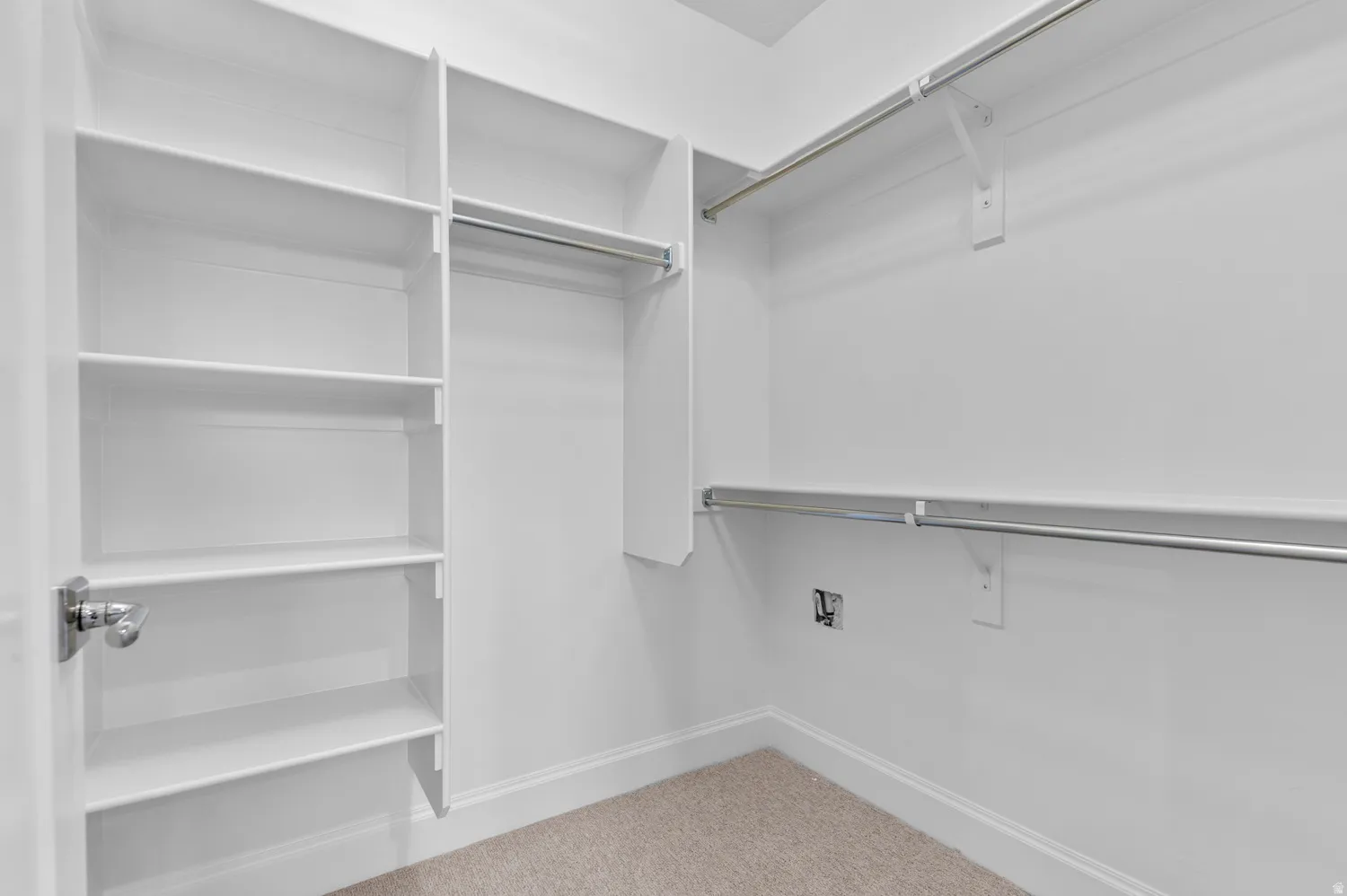 Spacious closet featuring built-in shelving, dual hanging rods, light-colored carpeting, and crisp white trim