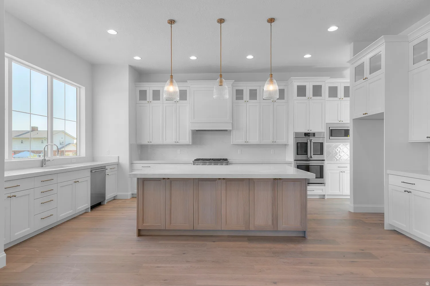 Modern kitchen featuring a two-toned island with a light wood-finish base, white perimeter cabinetry, and light countertops