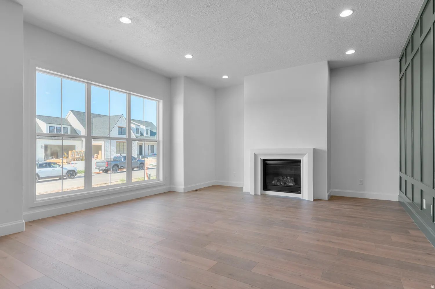 Spacious interior featuring wood-finish flooring, a contemporary fireplace with a white mantel, and a wall of transom windows