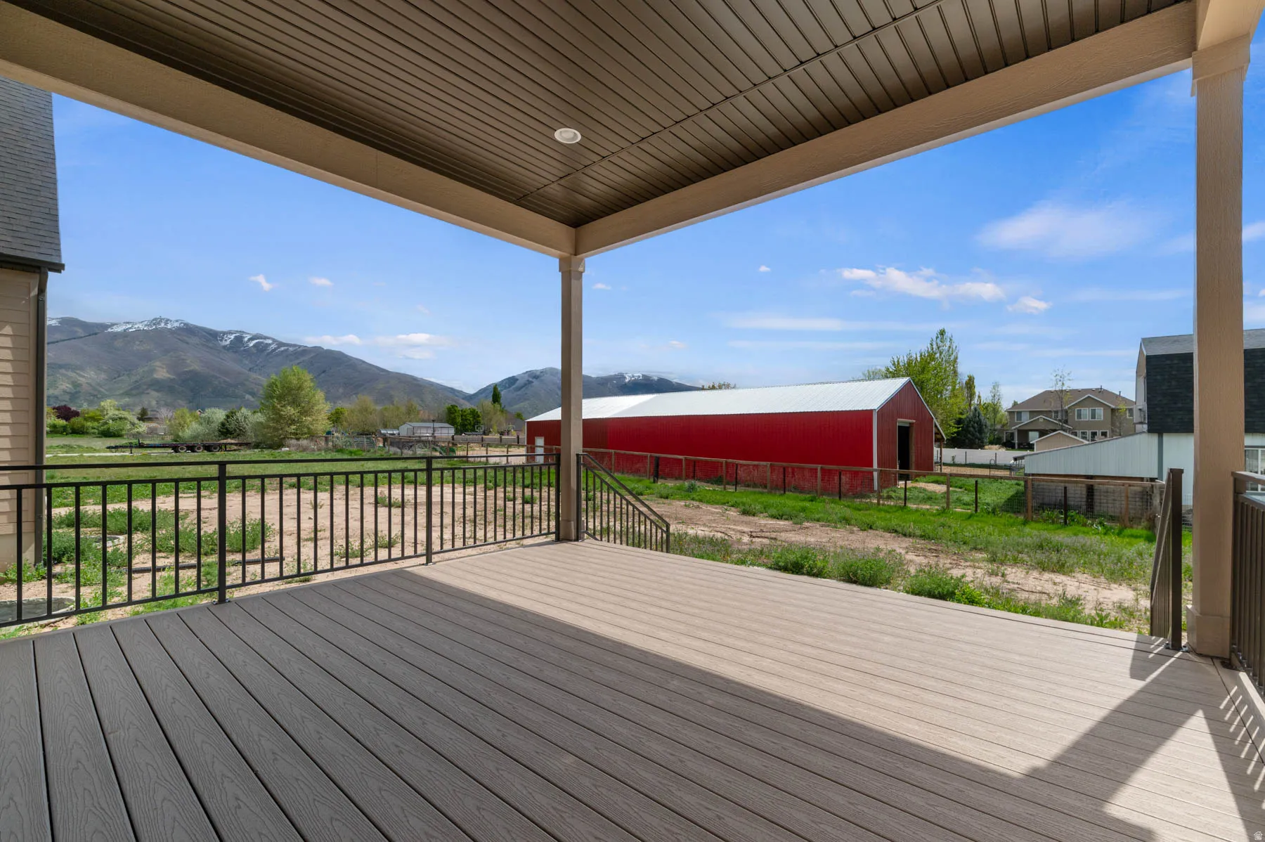 Covered outdoor deck with composite decking and black metal railings