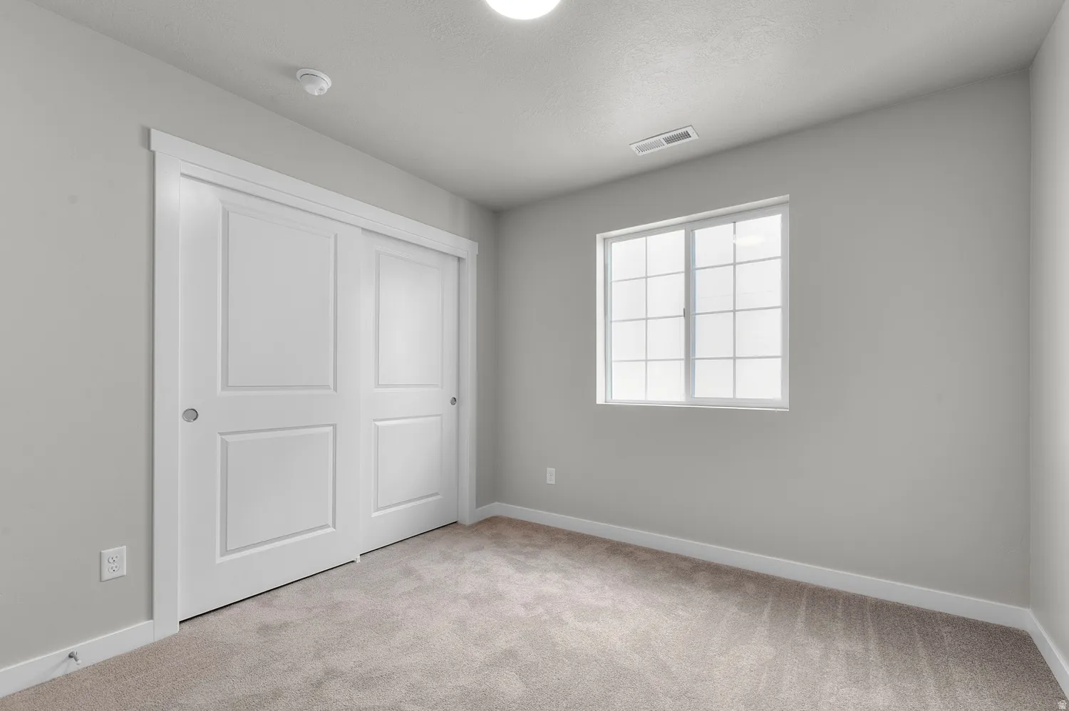 Carpeted room featuring a double-pane window with grids, white trim, light gray walls, and a recessed light fixture