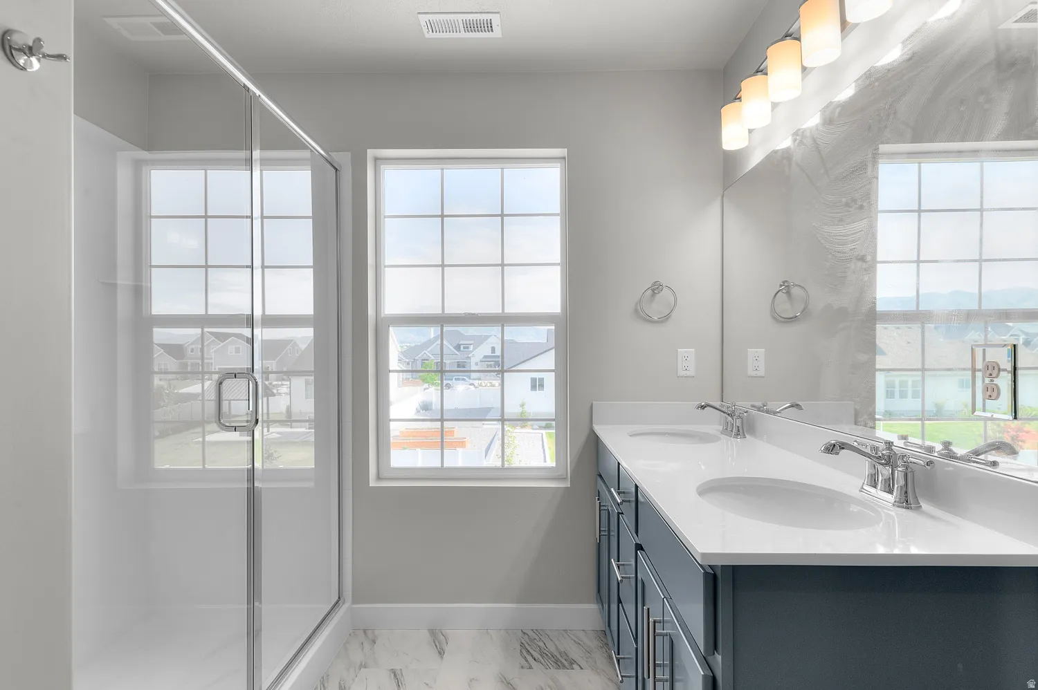 Bathroom featuring a dual vanity with undermount sinks, chrome faucets, and white countertops