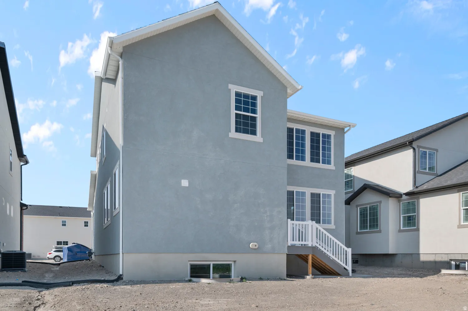 Two-story exterior with light blue stucco siding, white trim, and a white deck staircase