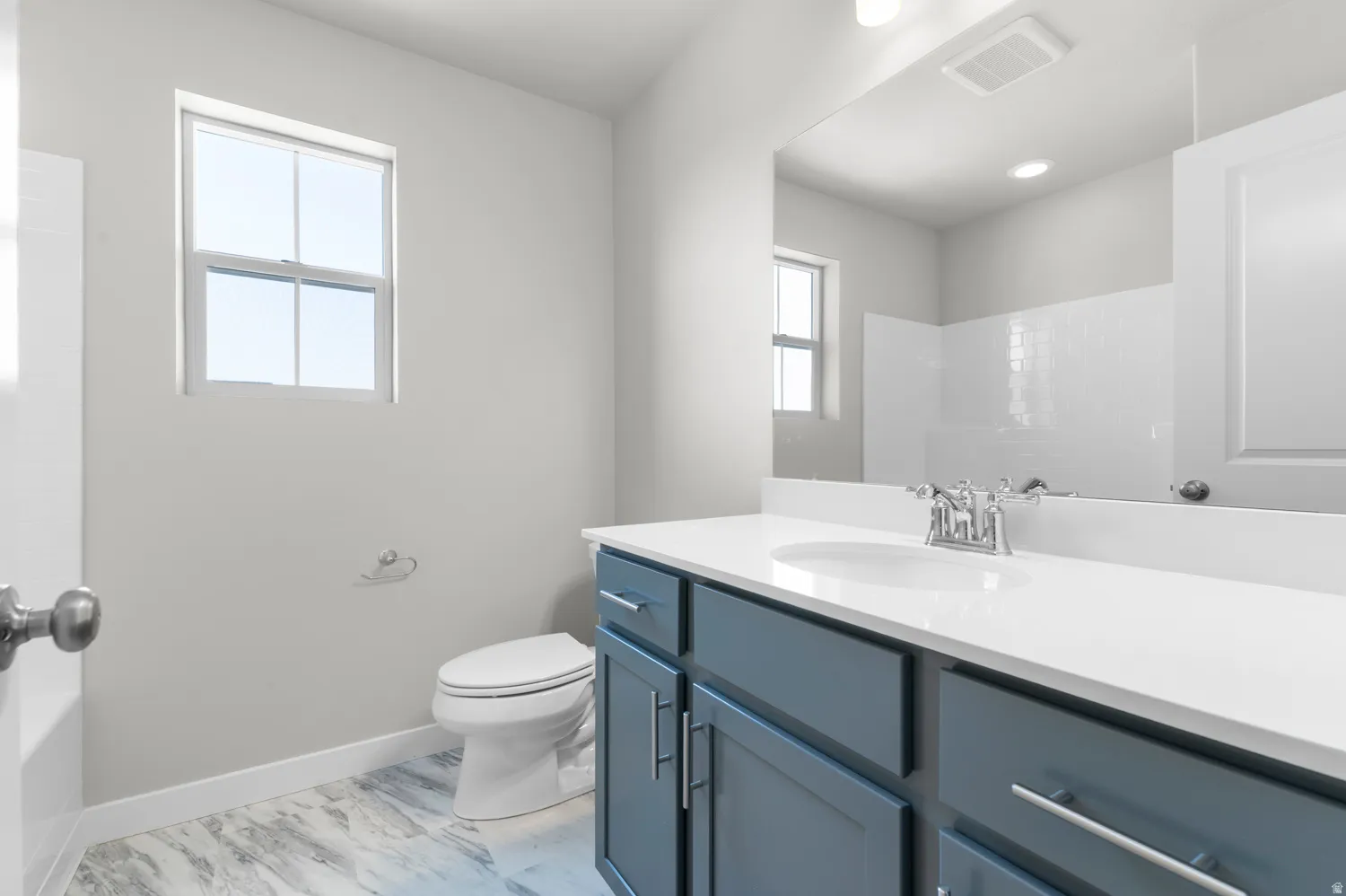 Bathroom vanity with a white countertop and integrated sink, chrome faucet, and blue shaker-style cabinetry with brushed nickel hardware