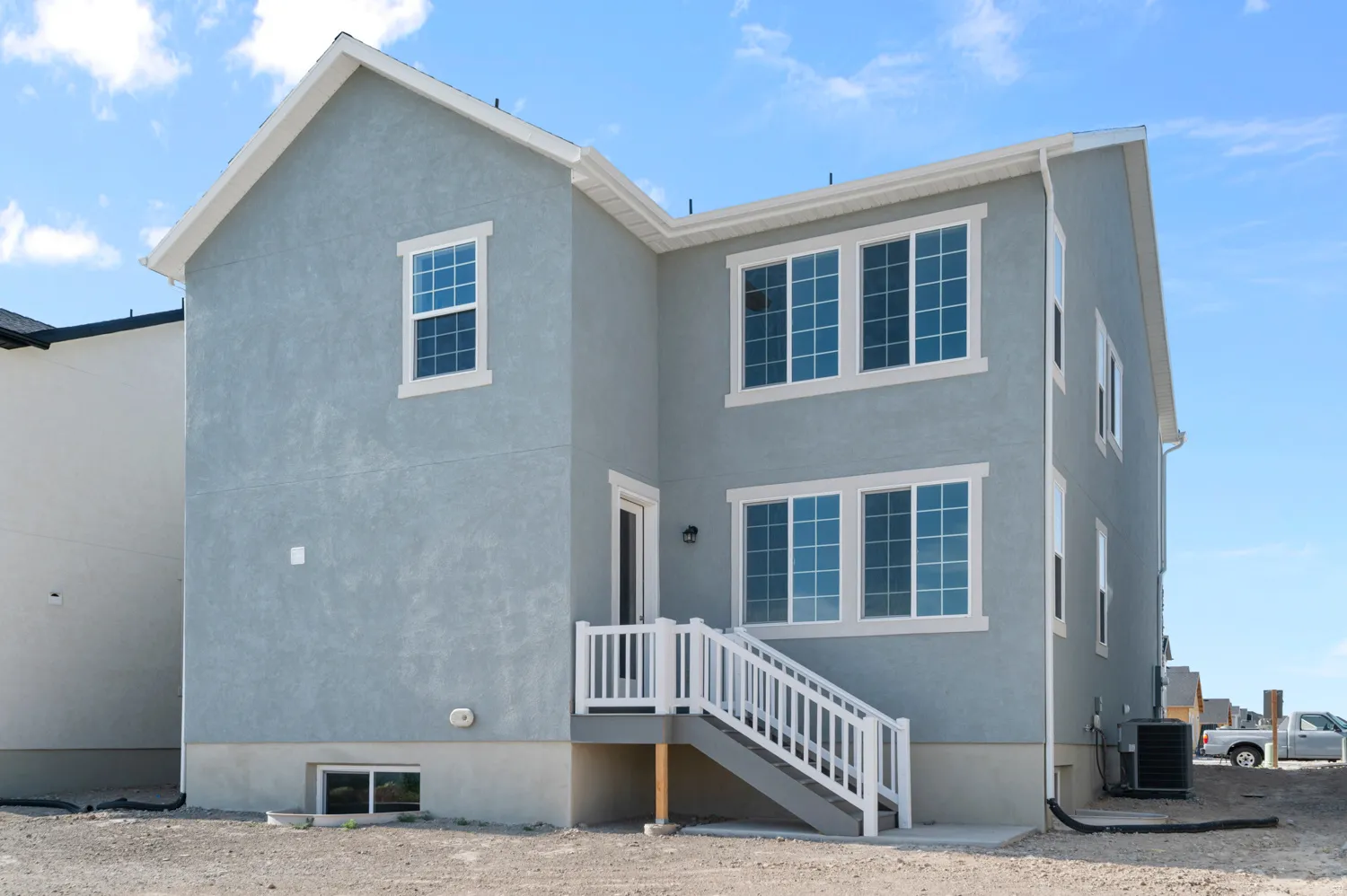 Blue stucco exterior with white trim windows and matching white deck railing
