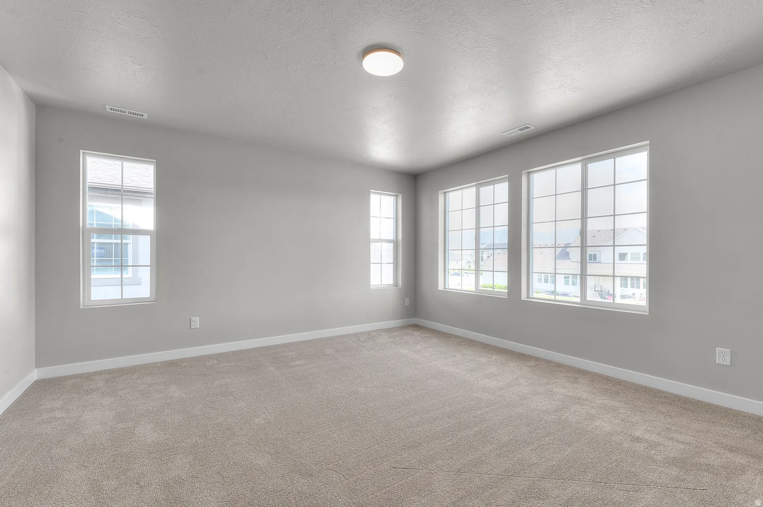 Spacious room featuring neutral carpeting and light gray wall paint