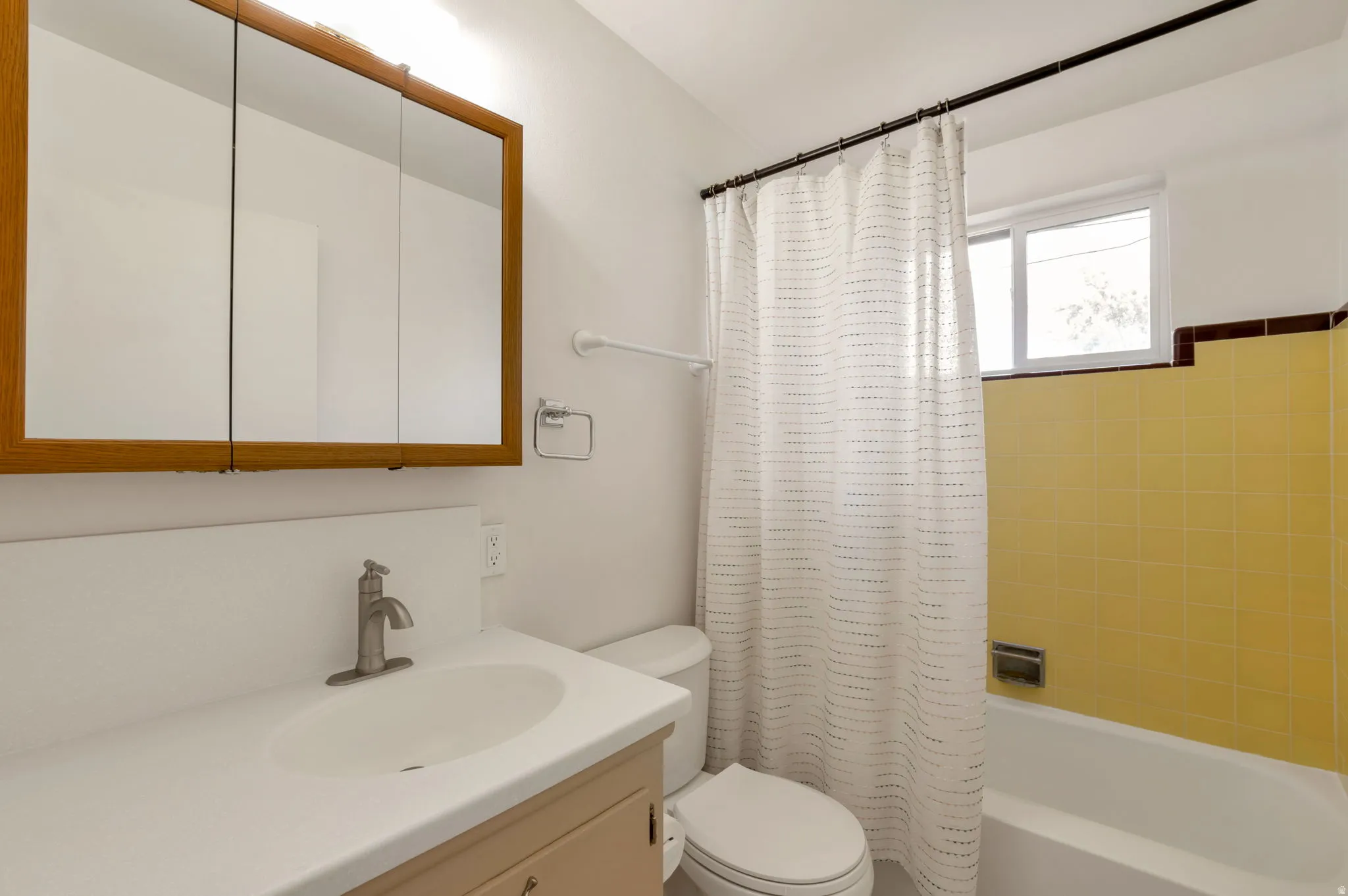 Bathroom featuring a vanity with an integrated sink, a brushed nickel faucet, and a wood-framed medicine cabinet